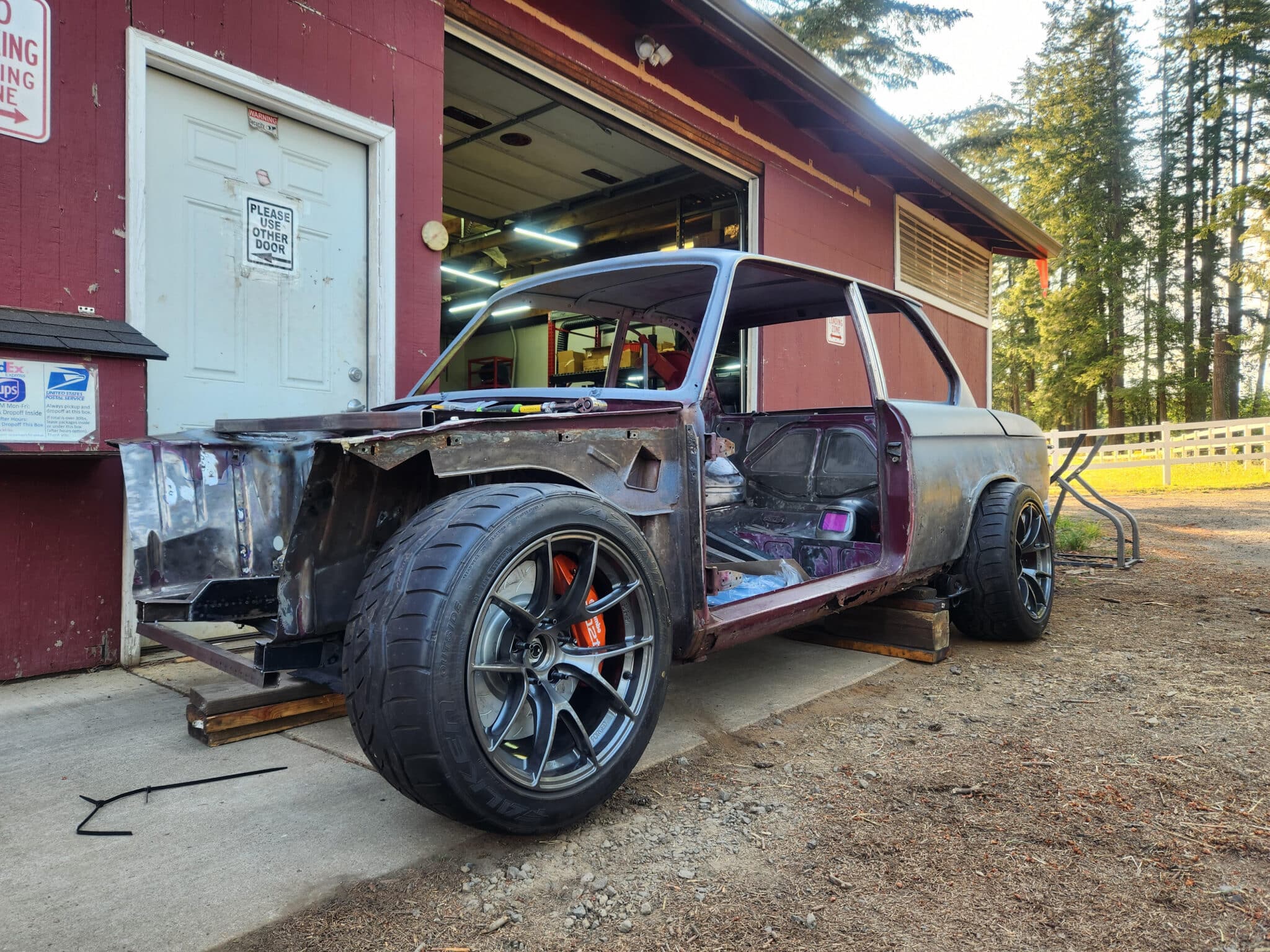 1972 BMW 2002 shell stripped and gutted outside the Rogue Fabrication shop in Sandy Oregon with E46 suspension and performance wheels fitted