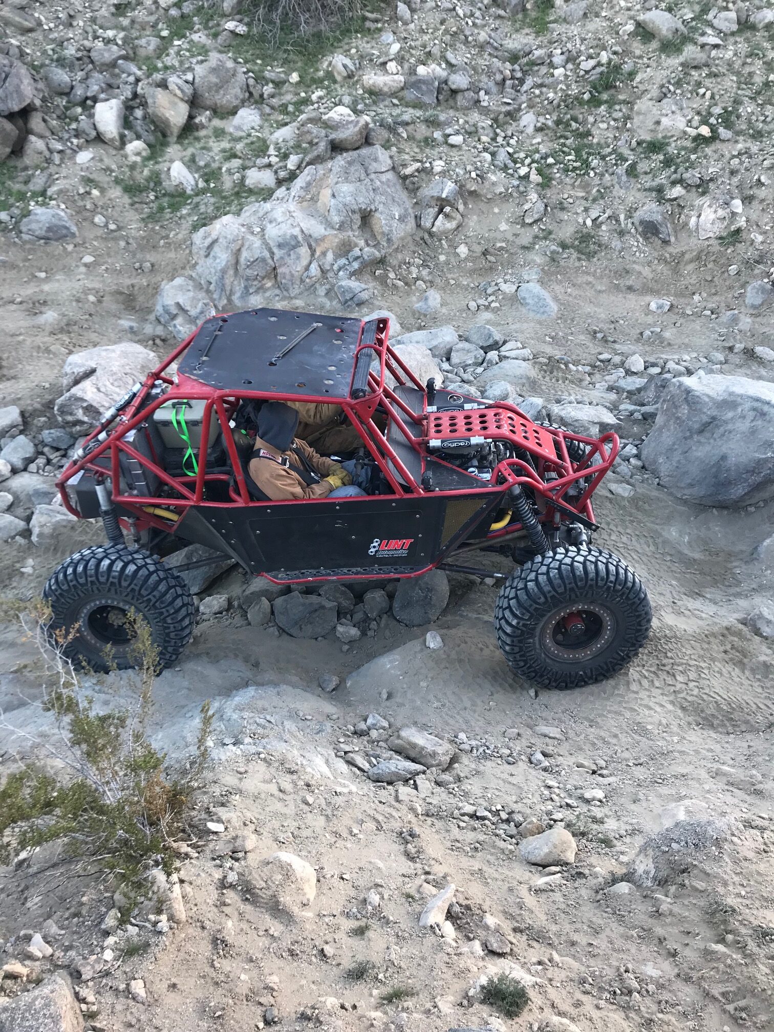 Red Ultra4 buggy navigating rock section at King of the Hammers showing full cage structure
